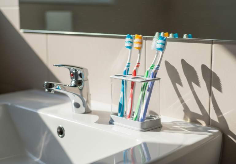 햇살 비치는 욕실 세면대 위의 칫솔들